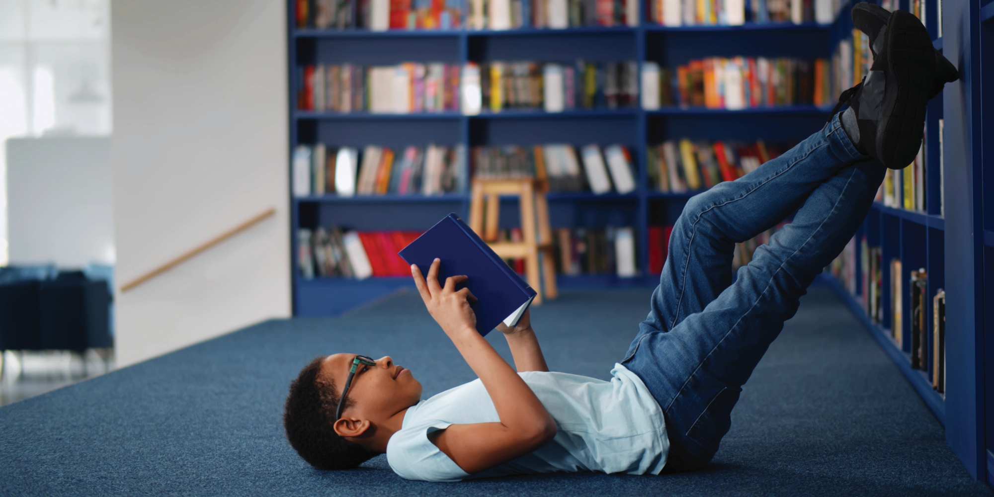 A young child reading a book while lying on the floor.