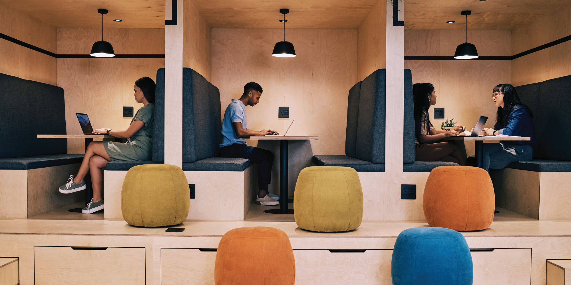 People using laptops and talking in work booths.